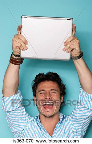 Stock Image - Man holding laptop up. Fotosearch