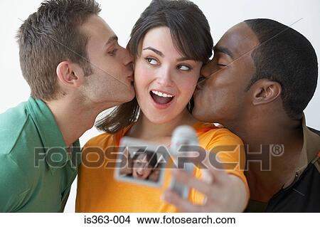 Picture - Men kissing woman with video camera. Fotosearch