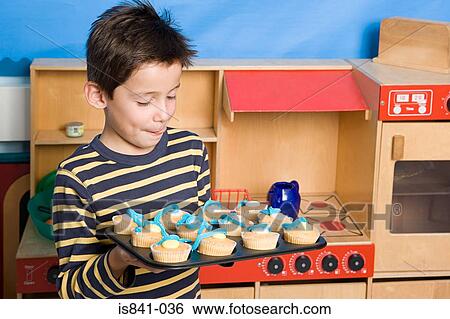Boy holding baking tray of fairy cakes View Large Photo Image Stock Photograph - Boy holding baking tray of fairy cakes. Fotosearch