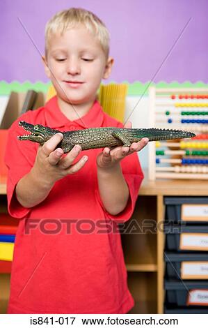 Stock Photo - Boy holding crocodile toy. Fotosearch
