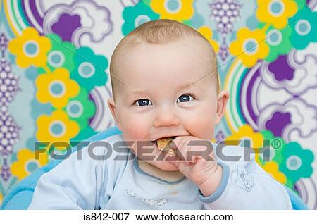 Stock Photo - Baby eating a biscuit. Fotosearch