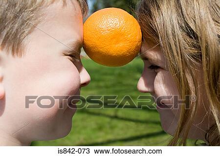 Stock Image - Boy and girl with orange between them. Fotosearch