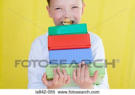 Boy eating snack on top of lunch boxes View Large Photo Image Stock Photography - Boy eating snack on top of lunch boxes. Fotosearch