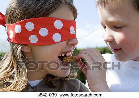 Boy feeding biscuit to girl in a blindfold View Large Photo Image Stock Photo - Boy feeding biscuit to girl in a blindfold. Fotosearch