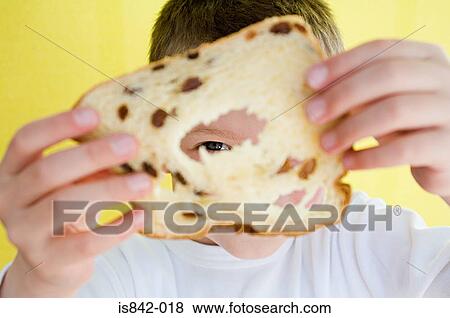 Stock Photo - Boy looking through raisin bread. Fotosearch