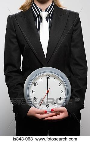 Businesswoman holding a clock View Large Photo Image Stock Image - Businesswoman holding a clock. Fotosearch