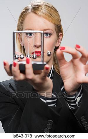 Businesswoman holding a newtons cradle View Large Photo Image Stock Photo - Businesswoman holding a newtons cradle. Fotosearch