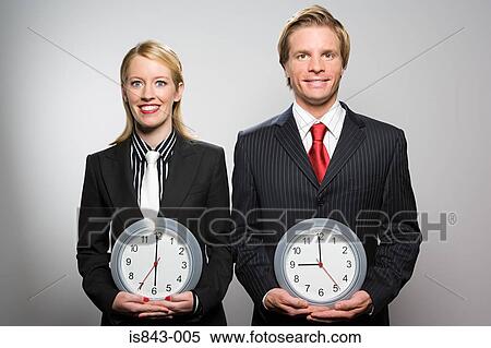 Two colleagues holding clocks View Large Photo Image Stock Photography - Two colleagues holding clocks. Fotosearch
