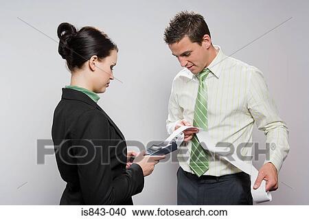 Stock Image - Two colleagues using calculator. Fotosearch