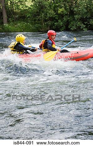 Stock Image - Two people white water rafting. Fotosearch