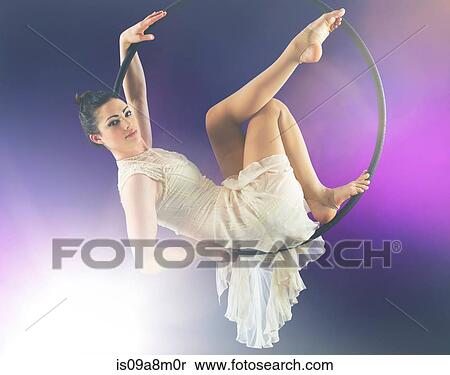 Aerialist poised on hoop against purple background View Large Photo Image Stock Photography - Aerialist poised on hoop against purple background. Fotosearch
