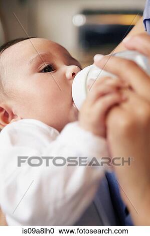 Stock Image - Baby girl drinking bottle of milk. Fotosearch