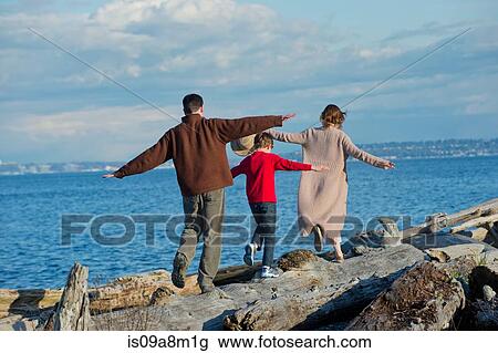 Back view of family walking along tree trunk at coast View Large Photo Image Stock Image - Back view of family walking along tree trunk at coast. Fotosearch