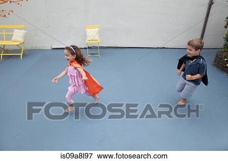 Boy and girl wearing superhero capes playing in back yard View Large Photo Image Stock Photo - Boy and girl wearing superhero capes playing in back yard. Fotosearch