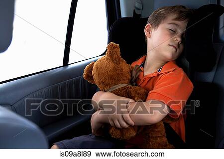 Boy asleep in child safety seat in car holding teddy bear View Large Photo Image Stock Photo - Boy asleep in child safety seat in car holding teddy bear. Fotosearch