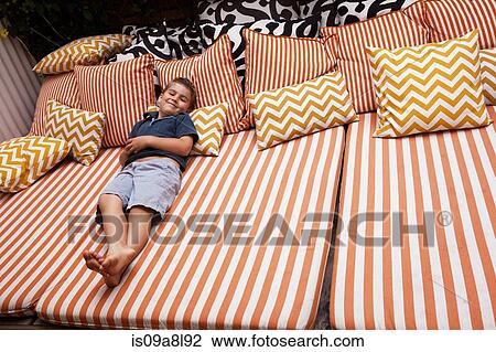 Boy relaxing on striped outdoor furniture with cushions View Large Photo Image Stock Image - Boy relaxing on striped outdoor furniture with cushions. Fotosearch