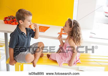 Brother and sister eating ice lollies on bench indoors View Large Photo Image Stock Photography - Brother and sister eating ice lollies on bench indoors. Fotosearch