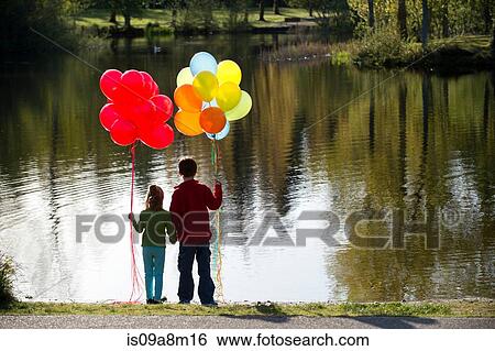 Brother and sister in front of lake with bunches of balloons View Large Photo Image Stock Photograph - Brother and sister in front of lake with bunches of balloons. Fotosearch