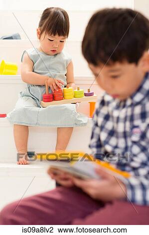 Stock Image - Brother and sister playing with toys on stairs. Fotosearch