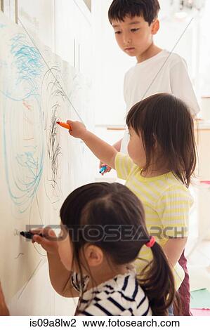 Stock Image - Brother and two young sisters drawing. Fotosearch