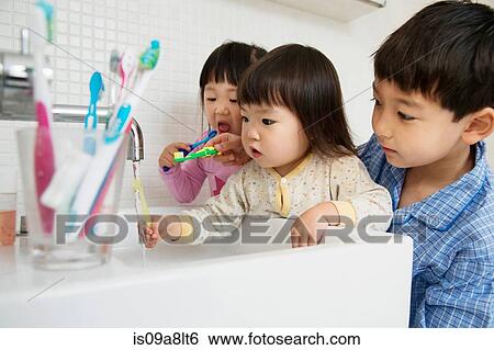 Stock Photograph - Brother helping sisters to clean teeth. Fotosearch