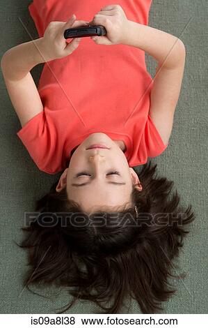 Stock Photo - Brunette girl lying on floor, from above. Fotosearch