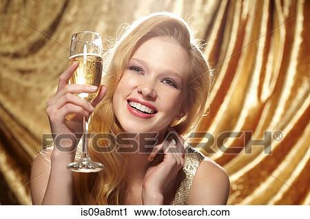 Stock Image - Candid portrait of young woman holding champagne flute. Fotosearch