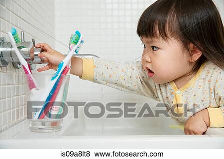 Stock Photo - Close up of girl toddler turning bathroom sink taps. Fotosearch
