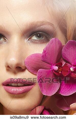 Stock Photo - Close up of young woman and orchids. Fotosearch
