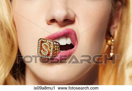 Stock Image - Close up of young woman with diamond ring in her mouth. Fotosearch