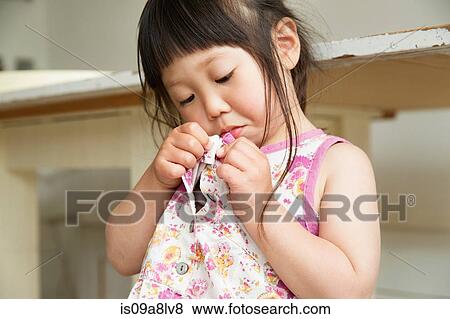 Stock Photo - Close up portrait of young girl fastening dress buttons. Fotosearch