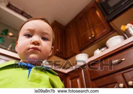 Stock Image - Close up portrait of young male toddler in kitchen. Fotosearch