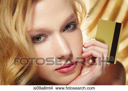 Picture - Close up portrait of young woman holding gold credit card. Fotosearch