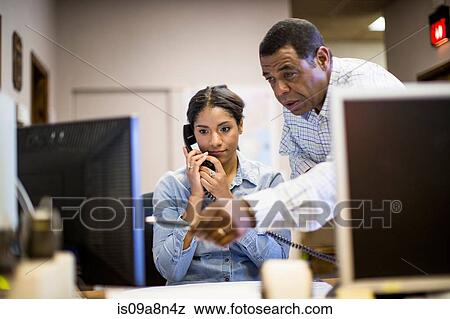 Colleagues in office looking at computer screen View Large Photo Image Stock Photo - Colleagues in office looking at computer screen. Fotosearch