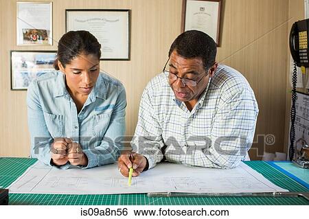 Colleagues looking at blueprint in office View Large Photo Image Stock Photograph - Colleagues looking at blueprint in office. Fotosearch
