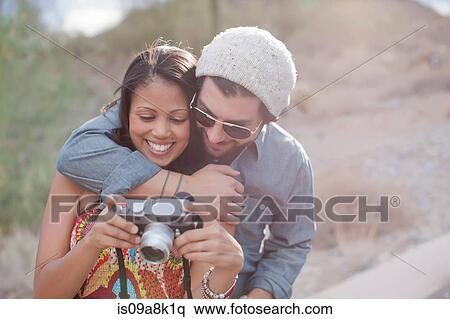 Couple embracing and holding camera on road trip, smiling View Large Photo Image Stock Photography - Couple embracing and holding camera on road trip, smiling. Fotosearch