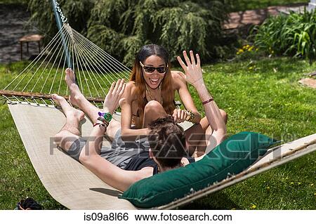 Stock Photograph - Couple in hammock, woman tickling man. Fotosearch