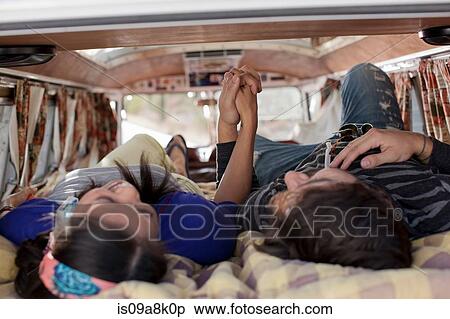 Stock Photography - Couple lying together in the back of camper van, holding hands. Fotosearch