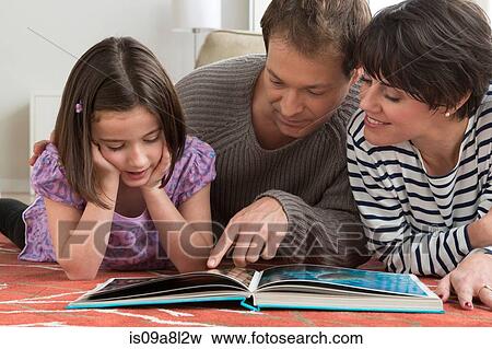 Stock Photo - Daughter looking at picture book with parents. Fotosearch