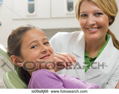 Stock Photograph - Dentist and young patient smiling, portrait. Fotosearch
