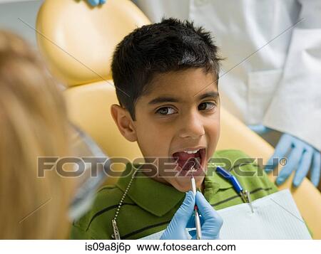 Dentist examining young patient's teeth View Large Photo Image Stock Photography - Dentist examining young patient's teeth. Fotosearch