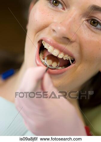 Stock Image - Dentist examining young woman's teeth, close up. Fotosearch