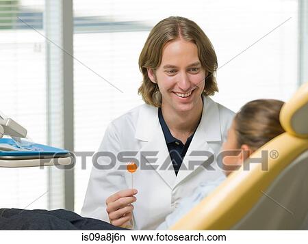 Dentist giving lollipop to young patient, smiling View Large Photo Image Picture - Dentist giving lollipop to young patient, smiling. Fotosearch
