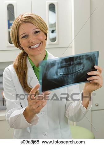 Stock Photo - Dentist looking at x-ray, smiling. Fotosearch