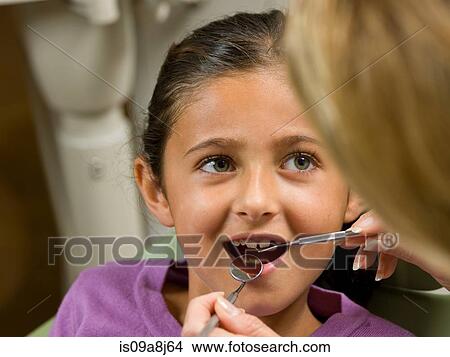 Dentist looking at young girl's teeth View Large Photo Image Picture - Dentist looking at young girl's teeth. Fotosearch
