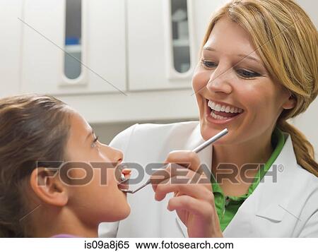 Dentist looking at young girl's teeth View Large Photo Image Stock Photography - Dentist looking at young girl's teeth. Fotosearch