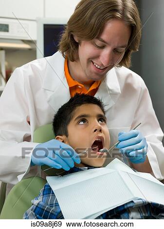 Dentist looking into boy's mouth View Large Photo Image Stock Photo - Dentist looking into boy's mouth. Fotosearch