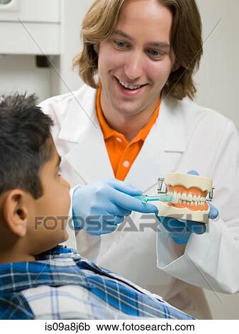 Dentist showing young boy how to brush teeth on model View Large Photo Image Stock Image - Dentist showing young boy how to brush teeth on model. Fotosearch