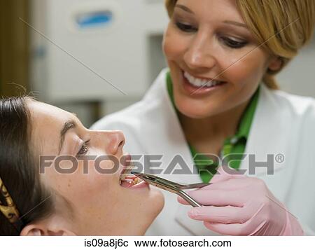 Dentist using dental pliers on young woman's braces View Large Photo Image Stock Image - Dentist using dental pliers on young woman's braces. Fotosearch