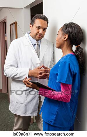 Doctor and nurse in discussion on hospital corridor View Large Photo Image Stock Image - Doctor and nurse in discussion on hospital corridor. Fotosearch